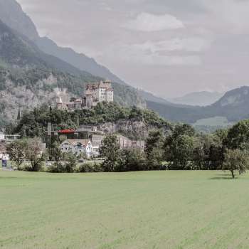 Vue majestueuse sur le château de Gutenberg à Balzers, entouré de champs verdoyants et des impressionnantes Alpes.