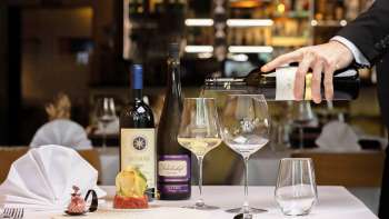 Un serveur sert du vin blanc pour accompagner un plat élégamment présenté au restaurant Alpspitz.