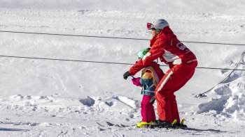 Une monitrice de ski prend le téléski à assiettes avec un enfant