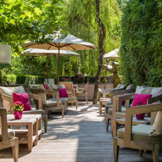 Groupe de sièges confortables avec coussins, plantes et parasols sur la terrasse du Park Hotel Sonnenhof à Vaduz, Liechtenstein