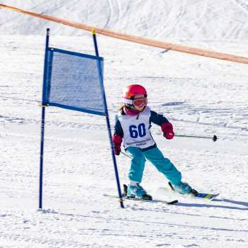 Un petit enfant avec un dossard passe les portes avec concentration lors de la course de ski pour enfants au Malbi-Park Malbun.