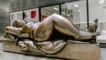 Figure féminine exubérante en bronze - l'œuvre d'art "Reclining Woman" de Fernando Botero pour attirer le regard dans le centre-ville.