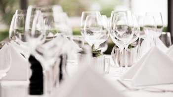 Gros plan sur plusieurs verres à vin empilés sur une table blanche avec des reflets lumineux.