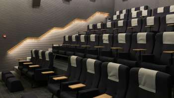 Salle de cinéma moderne au Skino de Schaan avec des sièges confortables, des petites tables et un éclairage tamisé.