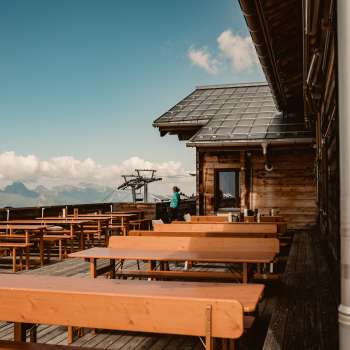 Bancs en bois vides sur la terrasse panoramique de la cabane Sareis avec vue sur les Alpes - idéal pour une pause pendant une randonnée ou un trajet en téléphérique.