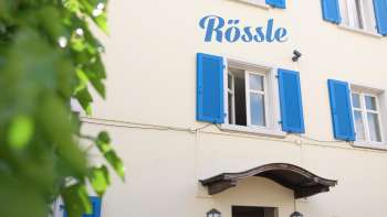 Vue extérieure du restaurant Rössle avec des volets bleus et une entrée confortable.