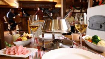 Gros plan sur un service à fondue au fromage avec du pain frais, des légumes et du vin dans une ambiance élégante