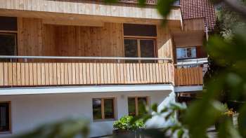 Vue extérieure de la maison d'hôtes du camping Mittagsspitze avec façade en bois et balcon dans un environnement proche de la nature