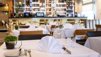  Table dressée avec goût au restaurant Alpspitz avec vue sur le bar en arrière-plan.