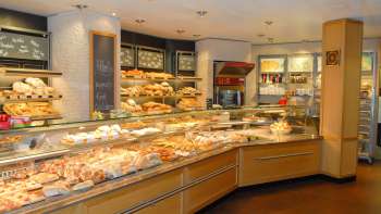 Vue sur l'espace de vente de la boulangerie pâtisserie Amann avec un comptoir rempli et de nombreuses friandises