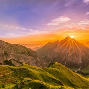 Coucher de soleil derrière les sommets près de Malbun au Liechtenstein avec des alpages, des chemins de montagne et une lumière dorée
