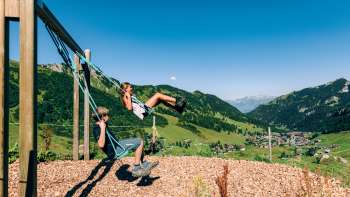 Deux enfants se balancent avec la vue sur Malbun