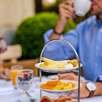 Petit déjeuner avec de la charcuterie, du fromage et des fruits frais sur un plateau à Vaduz, pendant qu'un client prend un café