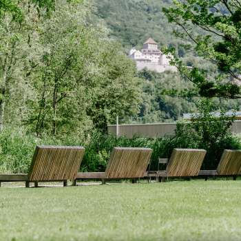 Pelouse avec chaises longues en bois avec vue sur le château de Vaduz