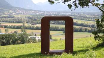 Sculpture "Resonare" en métal rouillé sur la colline de Krest avec vue sur la vallée du Rhin et les montagnes en arrière-plan.