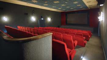 Vue latérale de la salle de cinéma de l'Altes Kino Vaduz avec des fauteuils rouges et un éclairage d'ambiance.