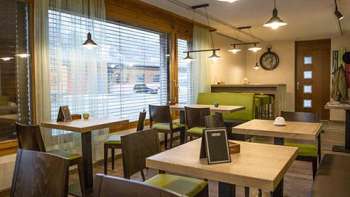 Bistrot moderne à l'ambiance chaleureuse, avec des tables en bois et des bancs verts stylés