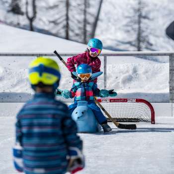 Famille patinant à Malbun, enfant assis sur un patin à glace en forme d'animal.