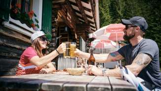 Deux personnes trinquent avec des verres de bière devant le refuge Gafadurahütte dans les Alpes liechtensteinoises
