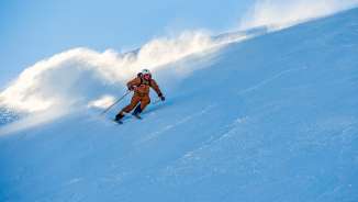 Marco Büchel dévale avec élan une piste enneigée à Malbun, la neige tourbillonne derrière lui.