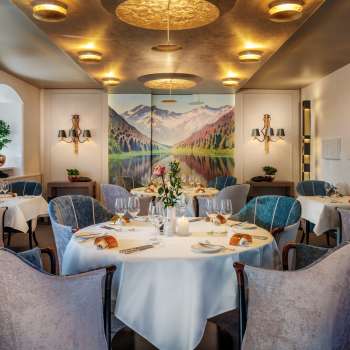 Tables dressées en rond avec verres à vin et bougies dans l'élégante salle à manger du Park Hotel Sonnenhof à Vaduz, Liechtenstein