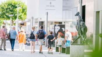 Des gens se promènent dans la zone piétonne moderne de Vaduz en passant devant le Musée des Beaux-Arts.