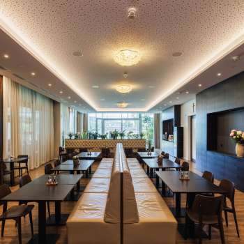 Salle à manger lumineuse du restaurant Kommod avec un design élégant et de grandes fenêtres.
