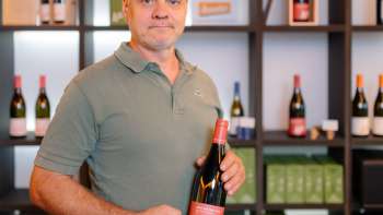 Harry Zech présente une bouteille de son vin dans un espace de vente stylé - la culture régionale du vin du Liechtenstein.