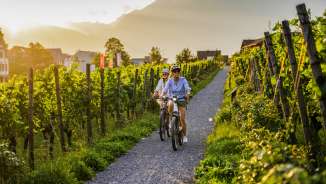 Deux cyclistes dans les vignobles du Liechtenstein au coucher du soleil - vélo électrique avec vue sur les Alpes et les vignes