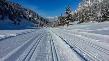 Piste de ski de fond fraîchement tracée à Steg avec vue panoramique sur le paysage alpin enneigé