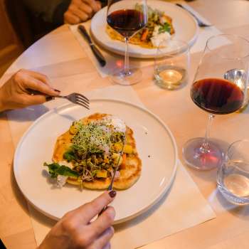 Gros plan sur un plat principal servi avec style et accompagné de vin rouge au Gasthof Au.