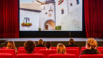 Des invités sont assis dans l'ancien cinéma de Vaduz et regardent le film « Fürstliche Momente ».