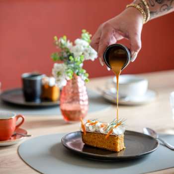 Dessert nappé de sauce caramel, avec en arrière-plan des tasses de café et une décoration de table stylée