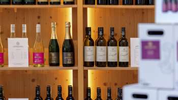 Intérieur de la cave du Prince du Liechtenstein avec des étagères en bois élégamment éclairées remplies de bouteilles et de cartons de vin.