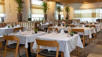 Vue sur le restaurant Alpspitz, aménagé avec style, avec des tables nappées de blanc et une atmosphère moderne et lumineuse.