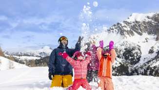 Une famille profite ensemble de la neige à Malbun - les enfants lancent joyeusement des boules de neige dans un décor de montagne hivernal.
