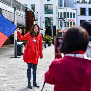 Une guide portant le drapeau du Liechtenstein accueille un groupe de touristes à Vaduz