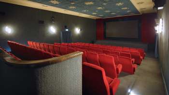 Vue latérale de la salle de cinéma de l'Altes Kino Vaduz avec des fauteuils rouges et un éclairage d'ambiance.