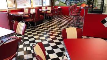 Intérieur du 1950 American Diner avec des tables rouges et un sol noir et blanc