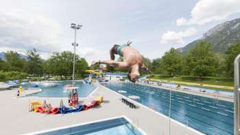 unge saute en salto du plongeoir d'un mètre dans le bassin de la piscine de Mühleholz - la joie estivale à l'état pur.
