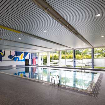Piscine couverte moderne Resch à Schaan avec art mural, grandes fenêtres et bassin de natation au Liechtenstein