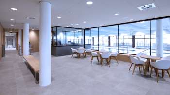 Coin salon lumineux dans la piscine intérieure de Triesen avec vue sur la piscine à travers la façade vitrée.