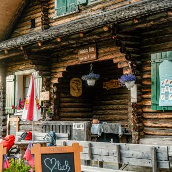 Entrée de la cabane : entrée rustique de la refuge Gafadurahütte avec façade en bois, fleurs multicolores et panneau d'information.