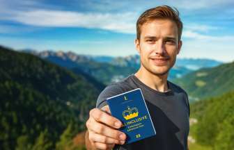 Passeport découvertes ALL INCLUSIVE L'homme montre le Passeport découvertes ALL INCLUSIVE avec un panorama de montagnes en arrière-plan