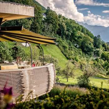 Terrasse ensoleillée avec des fleurs épanouies et des tables élégamment décorées avec vue sur la vallée