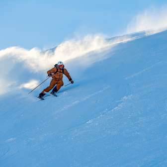 Marco Büchel dévale avec élan une piste enneigée à Malbun, la neige tourbillonne derrière lui.